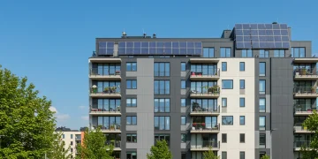 Fachada moderna de edificio residencial rehabilitado con paneles solares, simbolizando las ayudas estatales 2026 para viviendas.